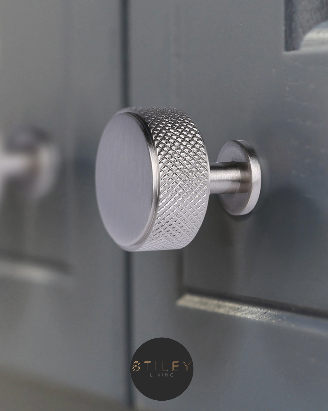 Round stainless cabinet handle on a grey cabinet door